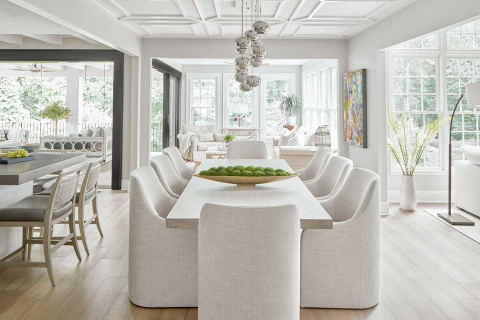 bright open concept home with white dining table and chairs opening up into sitting area and kitchen